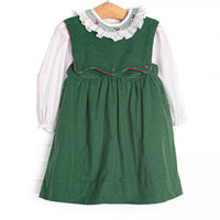 This dress features a green corduroy fabric, a button on bib, and white long sleeve top with a smocked scalloped collar