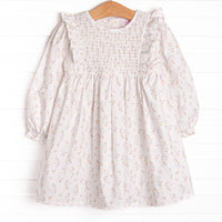 This dress features a blue floral print, a dainty smocking, and flutter trim.