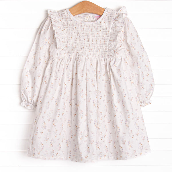 This dress features a blue floral print, a dainty smocking, and flutter trim.