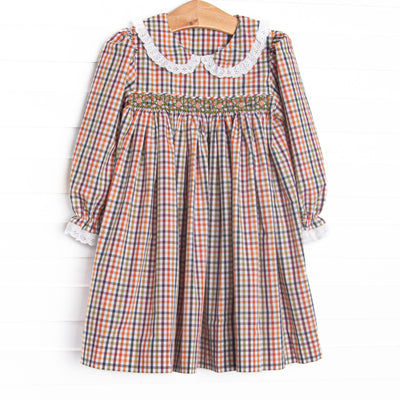 This dress features green plaid printed fabric, dainty smocking, a Peter Pan collar, and white eyelet lace trim.