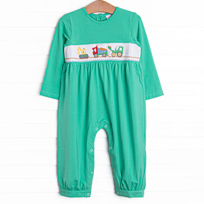  This romper features green knit material, snaps on the stride, and&nbsp; a construction themed smocking. 