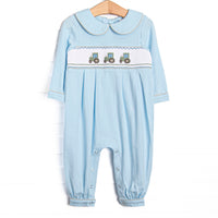 This romper features blue knit fabric, tractor smocking, a blue Peter Pan collar, and snaps along the stride to make changing a breeze.