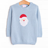  This sweater features a light blue material, buttons on the shoulder, and a santa icon. 