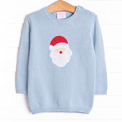  This sweater features a light blue material, buttons on the shoulder, and a santa icon. 