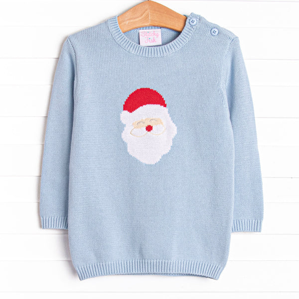  This sweater features a light blue material, buttons on the shoulder, and a santa icon. 