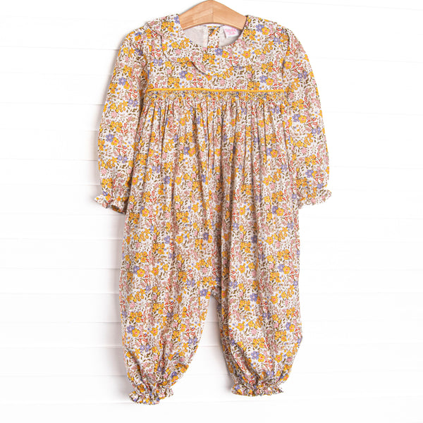  This romper features a yellow floral print, a scalloped collar, and a dainty smocking. 