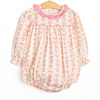 This bubble features pink floral and bow print, a pink ruffle collar, and long sleeves.