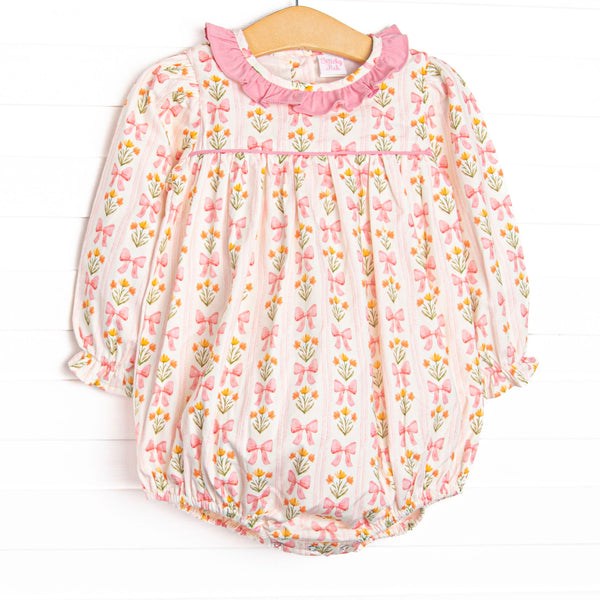 This bubble features pink floral and bow print, a pink ruffle collar, and long sleeves.