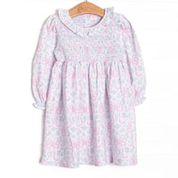  This dress features a floral and bow print, a ruffle collar, and chest smocking. 