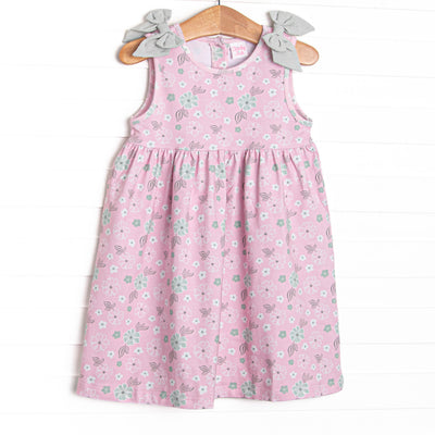 This dress features a pink floral, green gingham bow details, and button closure on the back