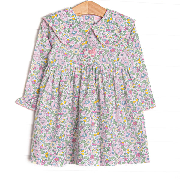 This dress features a pink flower print, a picot trimmed bib collar, and a French knot poodle embroidery.