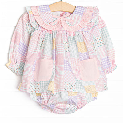  This skirted bubble features a pink quilt pattern, a ruffle Peter Pan collar, a pre tied bow, and pink front pockets. 