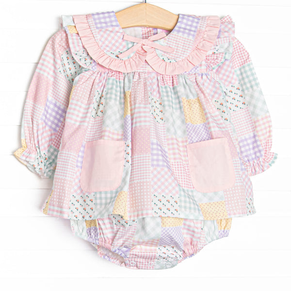  This skirted bubble features a pink quilt pattern, a ruffle Peter Pan collar, a pre tied bow, and pink front pockets. 