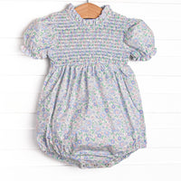 This bubble features a blue floral print, smocking across the chest, and puff sleeves.