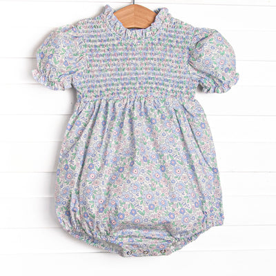 This bubble features a blue floral print, smocking across the chest, and puff sleeves.