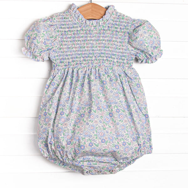 This bubble features a blue floral print, smocking across the chest, and puff sleeves.