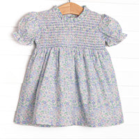 This dress features a blue floral print, smocking across the chest, and puff sleeves.
