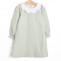This dress features a green plaid print, a scallop bib collar, and button closure on the back.