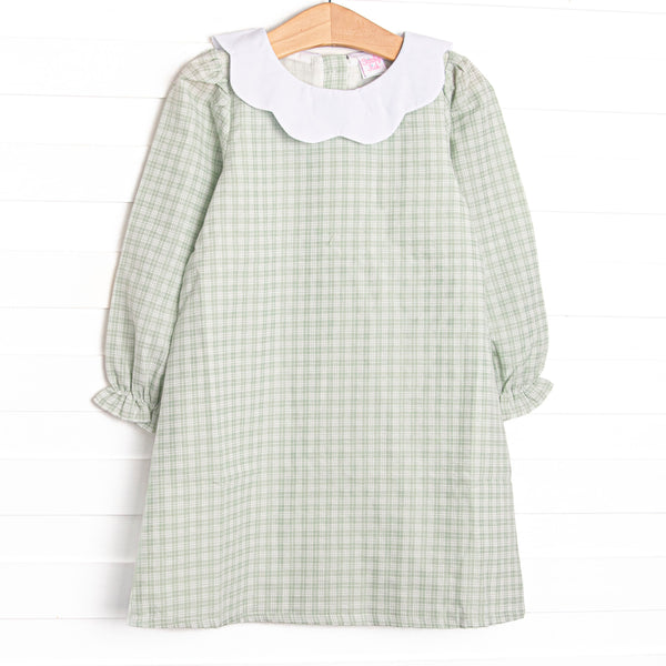 This dress features a green plaid print, a scallop bib collar, and button closure on the back.