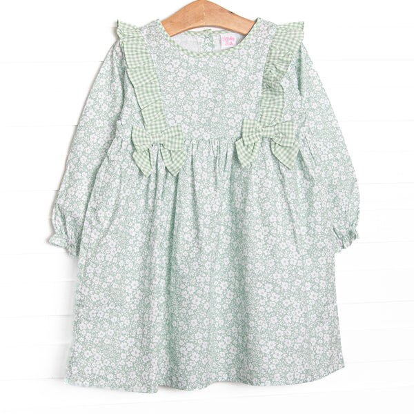  This dress features a green floral print, green ruffle trim, and green bows. 