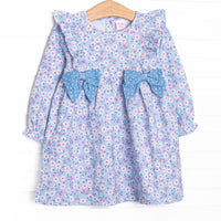  This dress features&nbsp; a blue floral print, a flutter trim, and blue polka bows. 