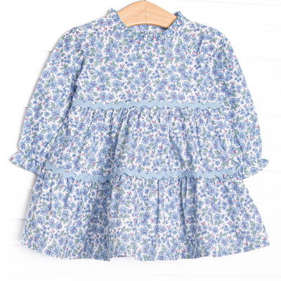 This dress features a blue floral print, tiered ruffles, and ruffles around the neck.
