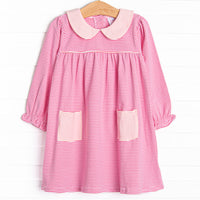  A pink Peter Pan collar, pockets and piping at the chest 