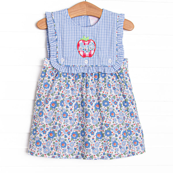  This dress features a blue floral print, a blue gingham button on bib, and red apple applique with ABC's on top. 