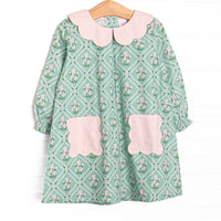 This dress features a tile and floral print, a pink scalloped collar, and pink scalloped front pockets.