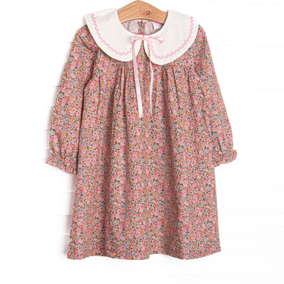  This dress features a pink floral print, a cream collar, and a satin bow. 