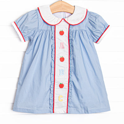  This dress features blue gingham material, puff sleeves, and abc and apple embroidery. 