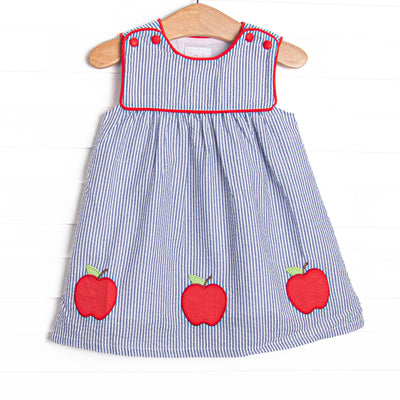 This dress features navy seersucker print, apple trio applique, and red piping.