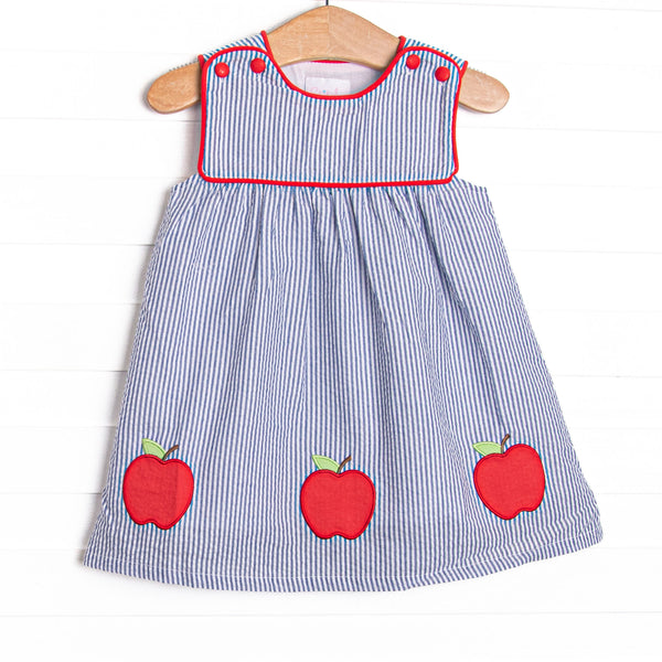 This dress features navy seersucker print, apple trio applique, and red piping.