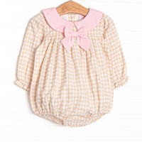  This bubble features a tan gingham print, a pink collar with bow, and snaps on the stride. 