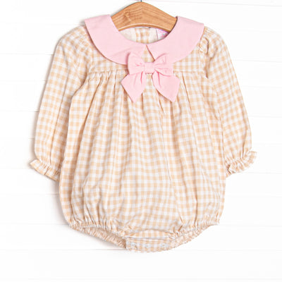  This bubble features a tan gingham print, a pink collar with bow, and snaps on the stride. 