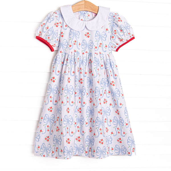This dress features a white blue bow and apple patterned material, puff sleeves, and red piping trim.