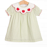 This dress features green seersucker material, apple trio applique on the collar, and red trim.