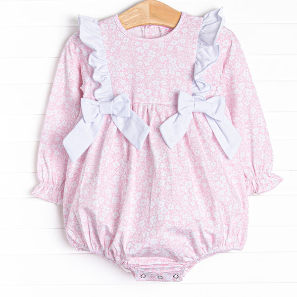  This bubble features a pink floral print, white ruffle trim, and white bows. 
