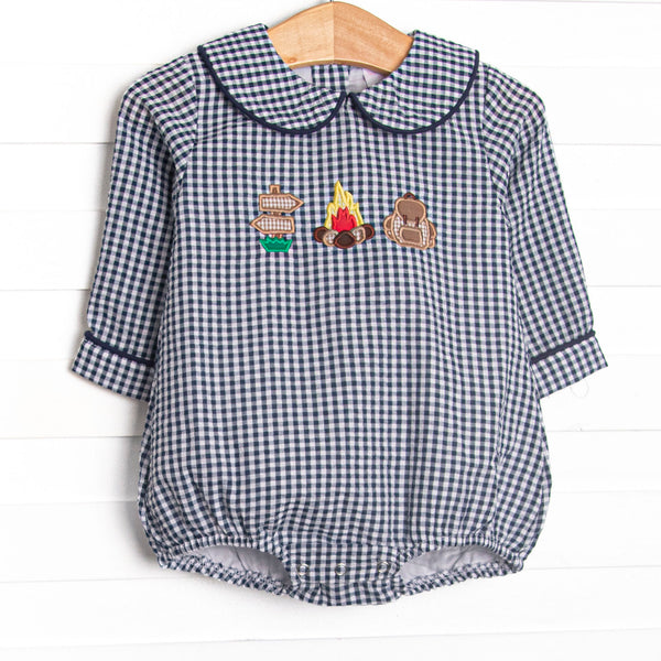  This bubble features a navy blue gingham print, a peter pan collar, and a camp inspired applique. 