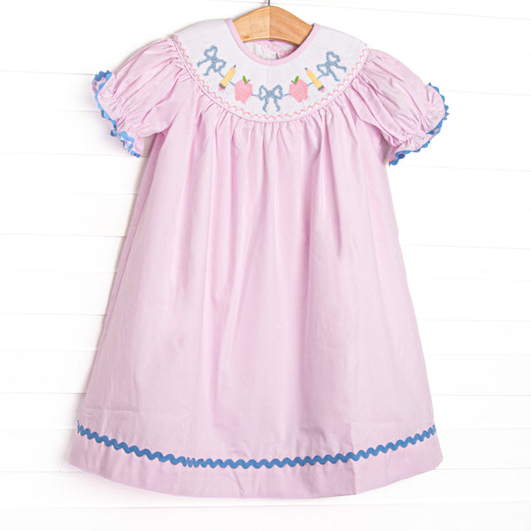  This dress features pink fabric, pencil, apple, and bow smocking, puff sleeves, and blue ric rac trim. 