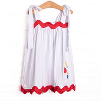 This dress features simple white fabric with tie straps, red ric rac trim, and school supply applique.