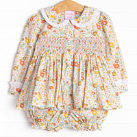 This set features an orange floral print, a peter pan collar with white ruffle trim, and a dainty smocking.