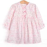 This dress features a pink dainty unicorn print, a trio of pink satin bows, and ruffle trim