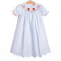 This dress features a blue seersucker print, puff sleeves, and&nbsp; a smocking of apples and pencils.
