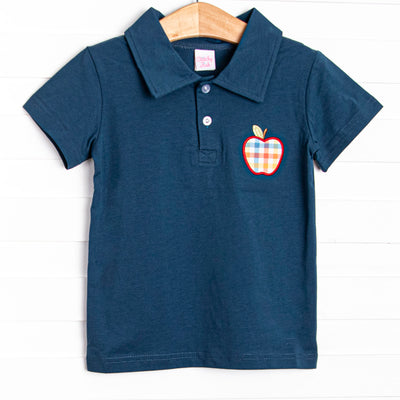 This top features a navy blue knit, polo collar, and a plaid apple applique.