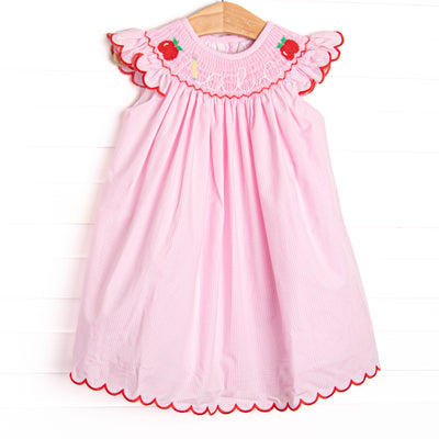 This dress features a pink gingham print, red ric rac trim, and an apple and abc smocking.