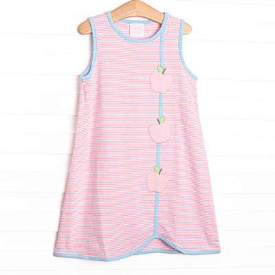This dress features a pink striped print, blue trim, and apple appliques.