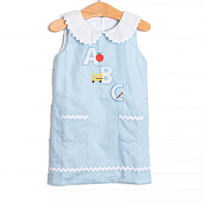 A sweet applique featured in blue bitty dot that is perfect for back to school! This woven dress will be a favorite for your little girl. Peter pan collar, button down back, and an ABC applique