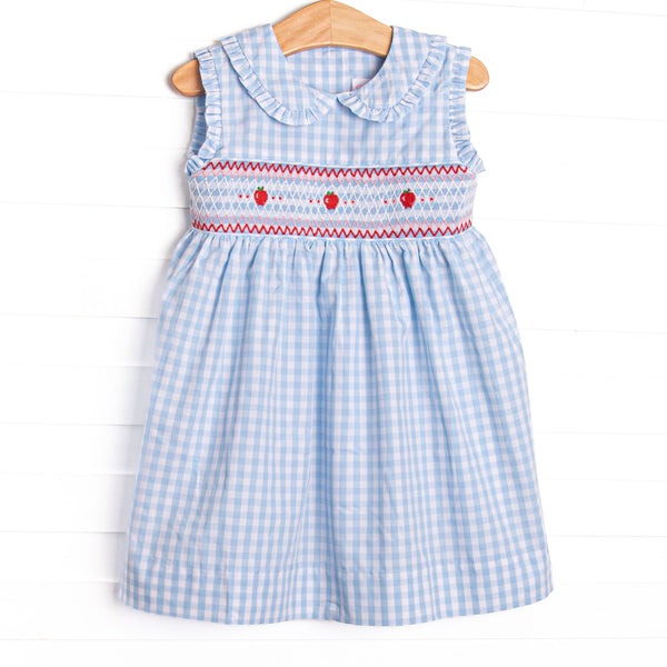 This dress features a blue gingham print, a peter pan collar, and an apple smocking.
