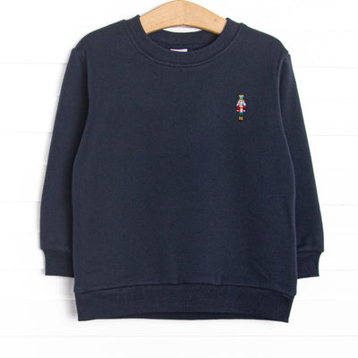  This sweatshirt features navy blue fleece fabric, a sugar plum soldier embroidery, and long sleeves. 